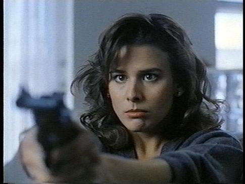 Image de la comédienne Krista Errickson braquant un pistolet droit devant, dans le film Killer Image