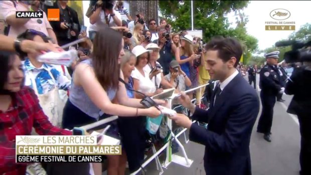 Xavier Dolan signe des autographes avant de monter les marches de Cannes pour la cérémonie de clôture (image-écran de la webdiffusion de Cannes 2016)