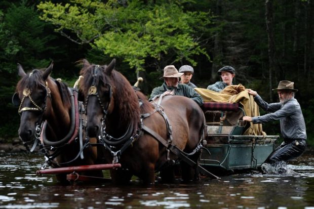 Image des comédiens Guy Thauvette (g.), Tristan Goyette Plante, Justin Leyrolles-Bouchard, Roy Dupuis (d.) traversant une rivière avec un chariot dans le film "Pieds nus dans l'aube" de Francis Leclerc