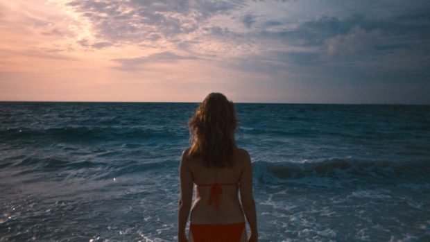Image extraite du film Isla Blanca - on y voit de dos la comédienne Judith Baribeau en bikini rouge faisant face à la mer