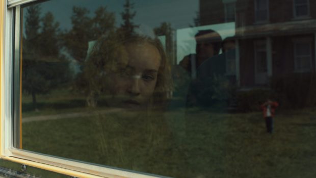 Image tirée de Une colonie de Geneviève Dulude-De Celles (pensive, une feune femme regarde par la fenêtre)
