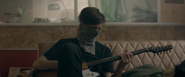 Emmanuel Schwartz dans le film Nous sommes Gold d'Éric Morin (le comédien joue de la guitare sur un divan avec un bandeau lui masquant presque tout le visage)