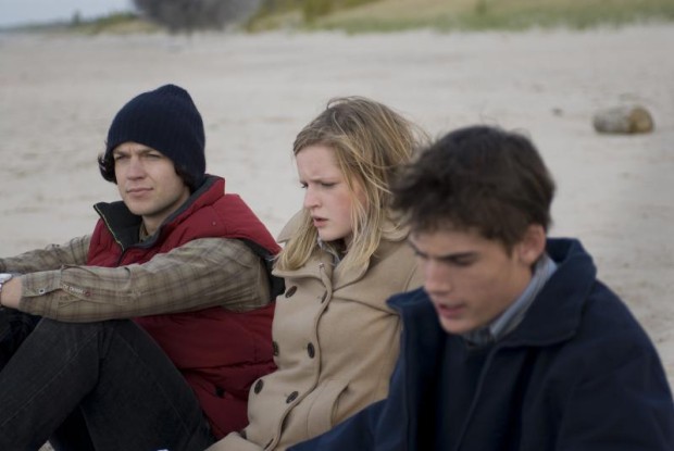 Image du film The Bend de Jennifer Kierans dans laquelle on voit trois jeunes, pensifs, assis sur une plage de sable 