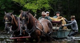 Image des comédiens Guy Thauvette (g.), Tristan Goyette Plante, Justin Leyrolles-Bouchard, Roy Dupuis (d.) traversant une rivière avec un chariot dans le film "Pieds nus dans l'aube" de Francis Leclerc