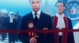 Image extraite du film Twentieth Century de Matthew Rankin (les yeux fermés, un homme coupe un cordon rouge, en signe d'inauguration)