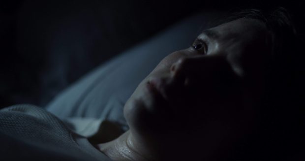 Lee Marshall dans Bleed With Me de Amelia Moses (dans le noir, gros plan sur le visage de la jeune femme, allongée et pensive)